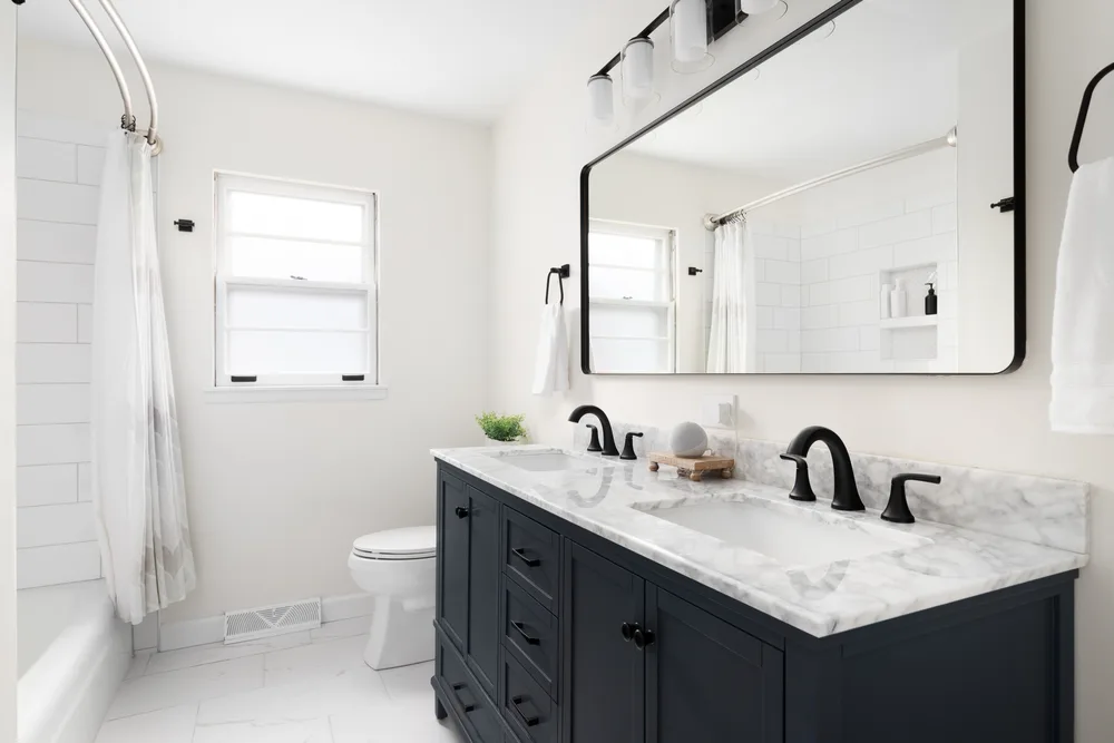 Navy double vanity with a white veined stone countertop and black fittings