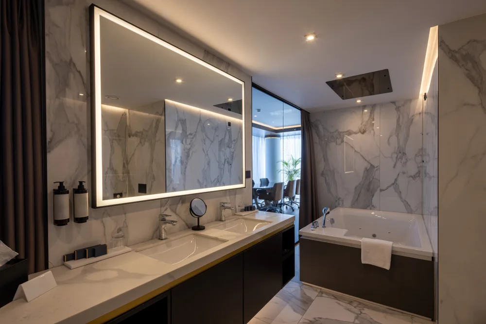 Hotel bathroom clad floor to ceiling in white veined stone