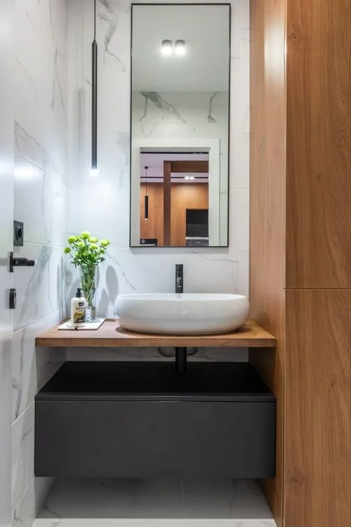Floating oak vanity with a stone basin and matte black fittings