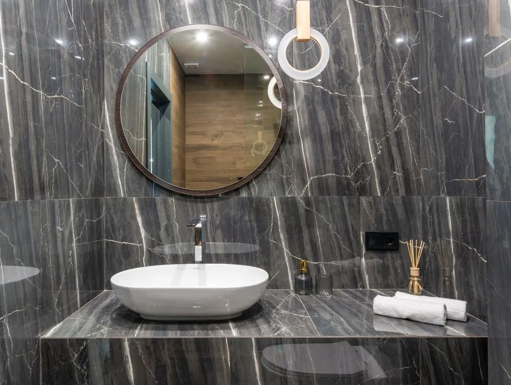 Twin round mirrors above a dark veined stone vanity