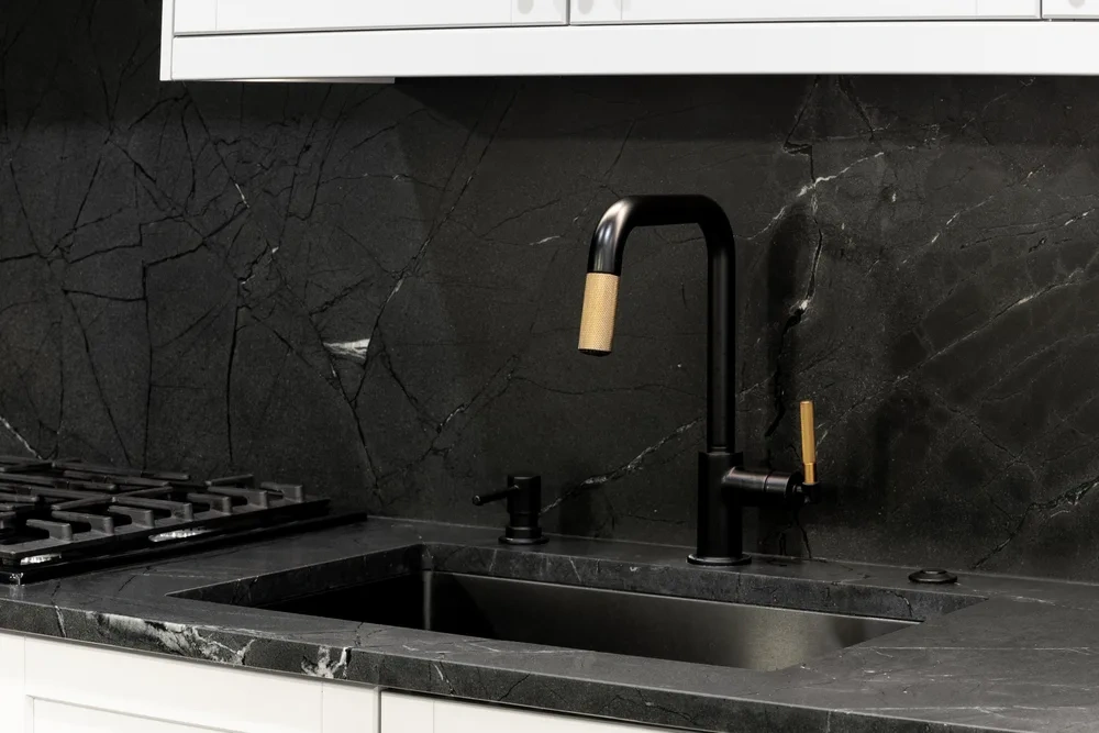 Matte black tap detailed against a polished stone surface