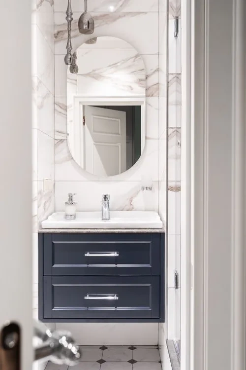 Arched mirror above a white marble vanity